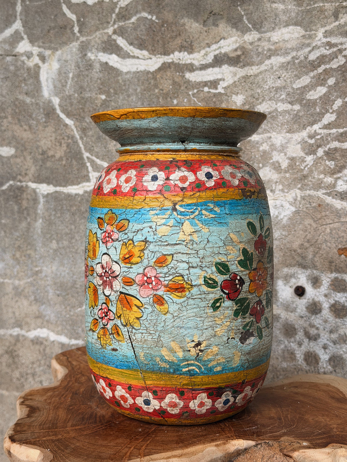 Beschilderde melkpot van dichtbij: turquoise buik met roze en gele bloemen en rode sierranden