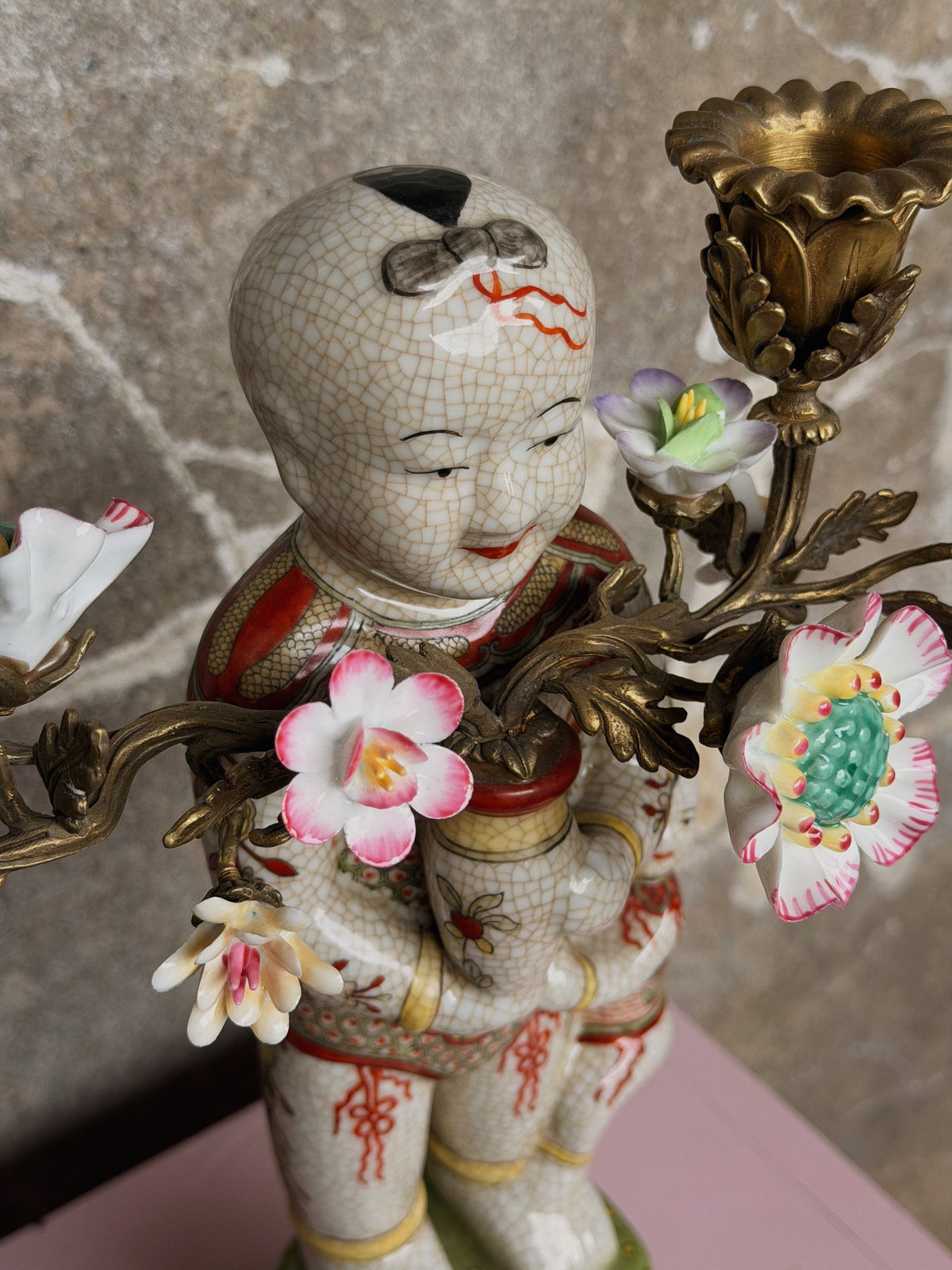 Detail van het gecraqueleerde kindergezicht met bloesems en een bronzen kaarshouder ernaast
